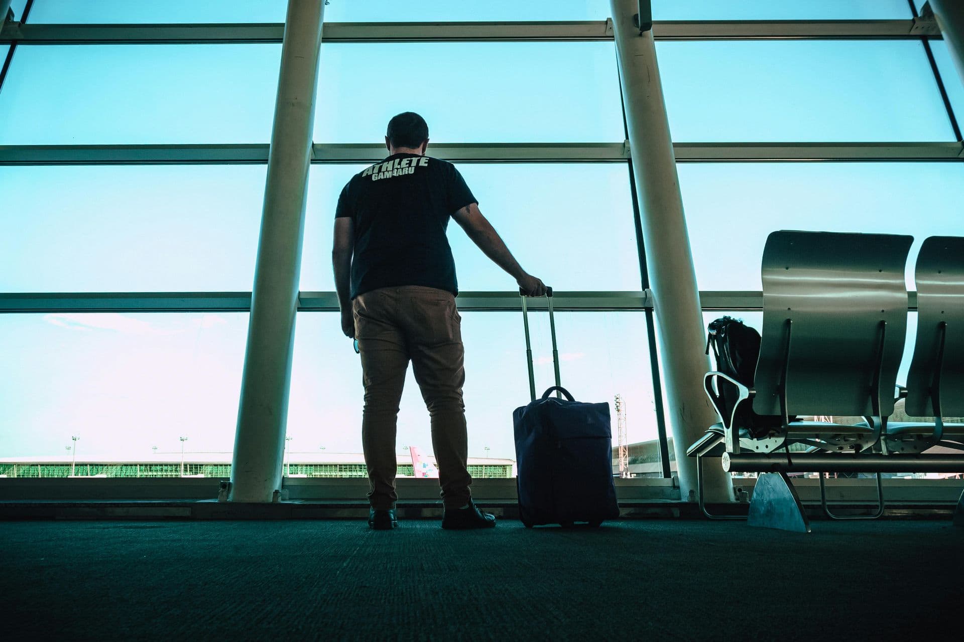 Traveller looking out of a terminal window at an aircraft on the apron